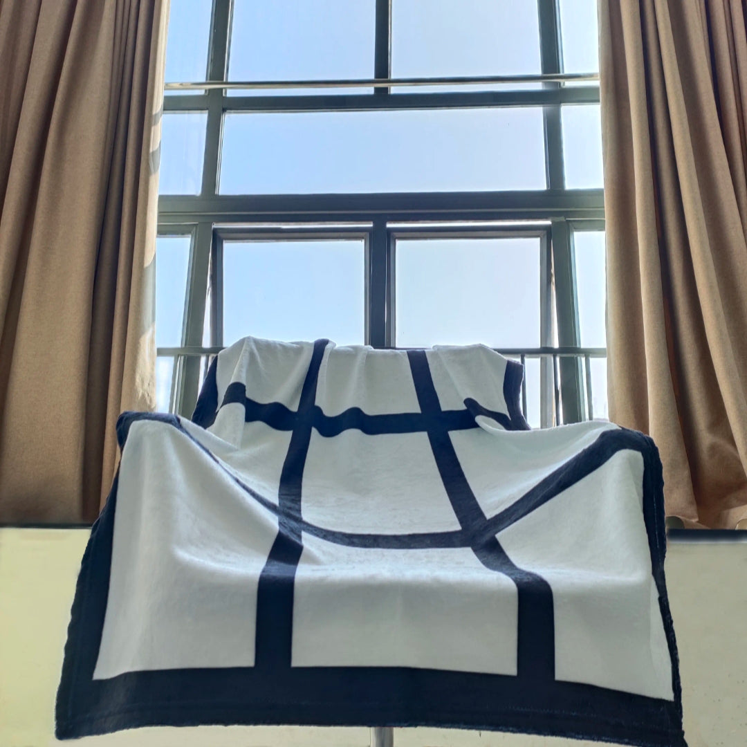 Nine-panel white blanket with black grid dividers near window